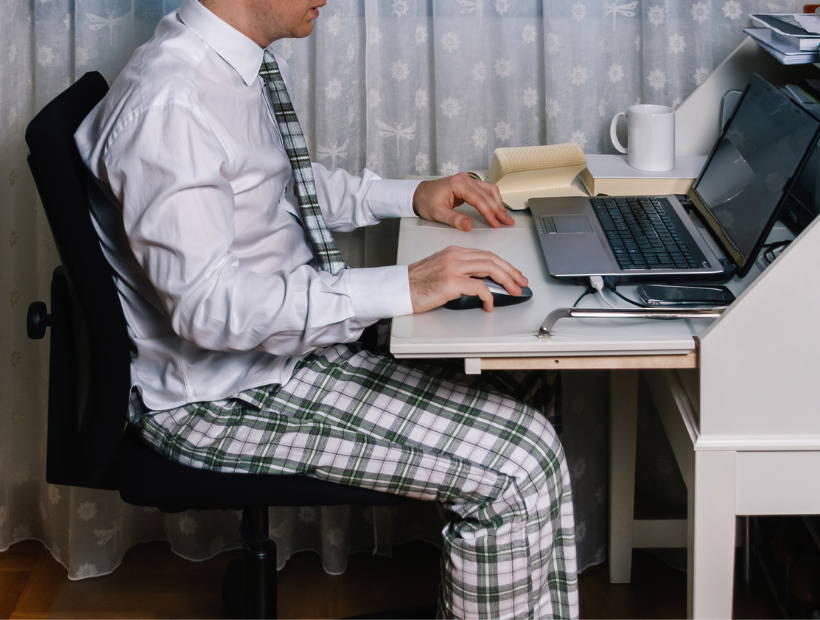 Business man working at a desk wearing black and white pj pants, a white button down and a tie that matches his pants 
