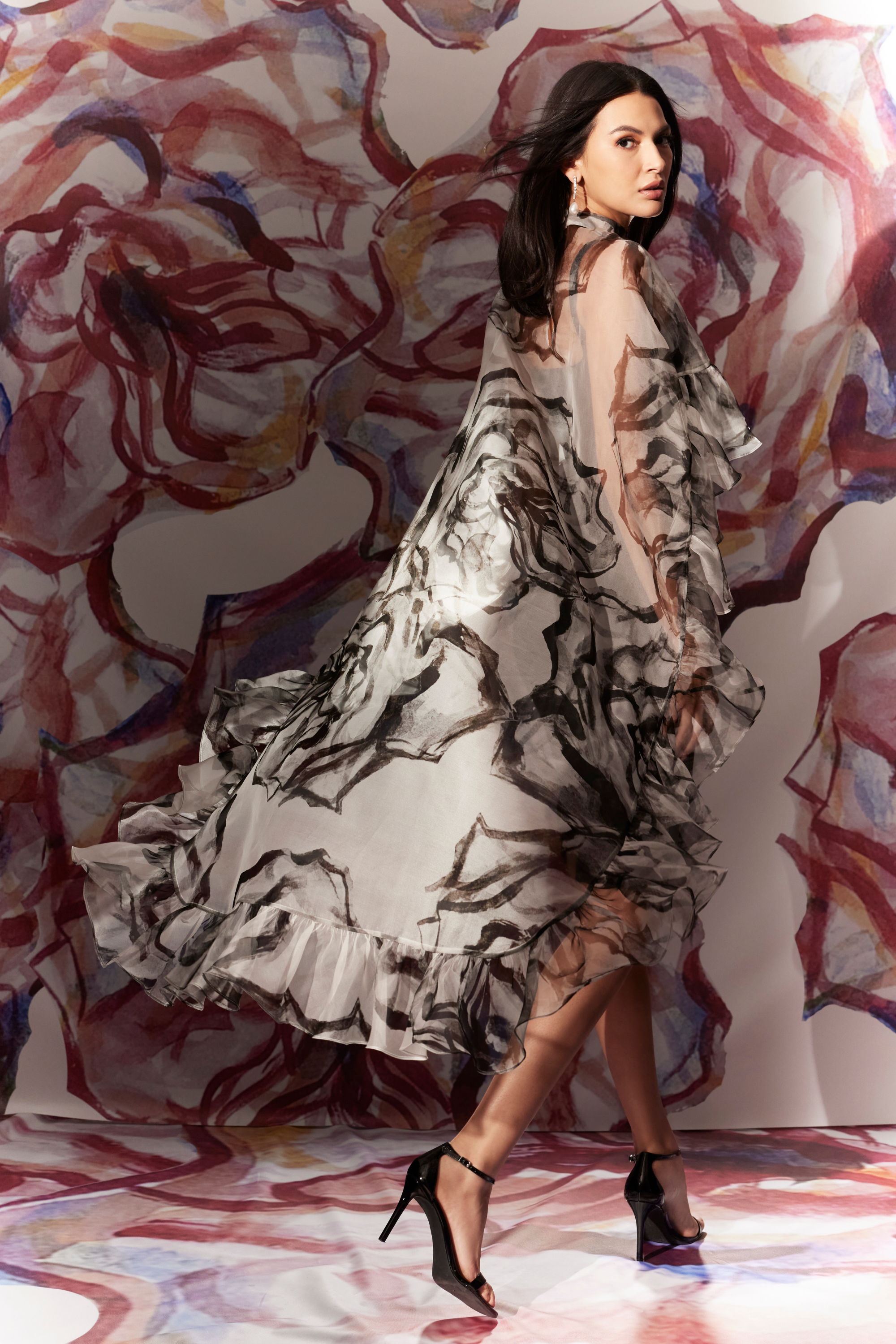 Woman in a flowing dress against a colorful abstract background.