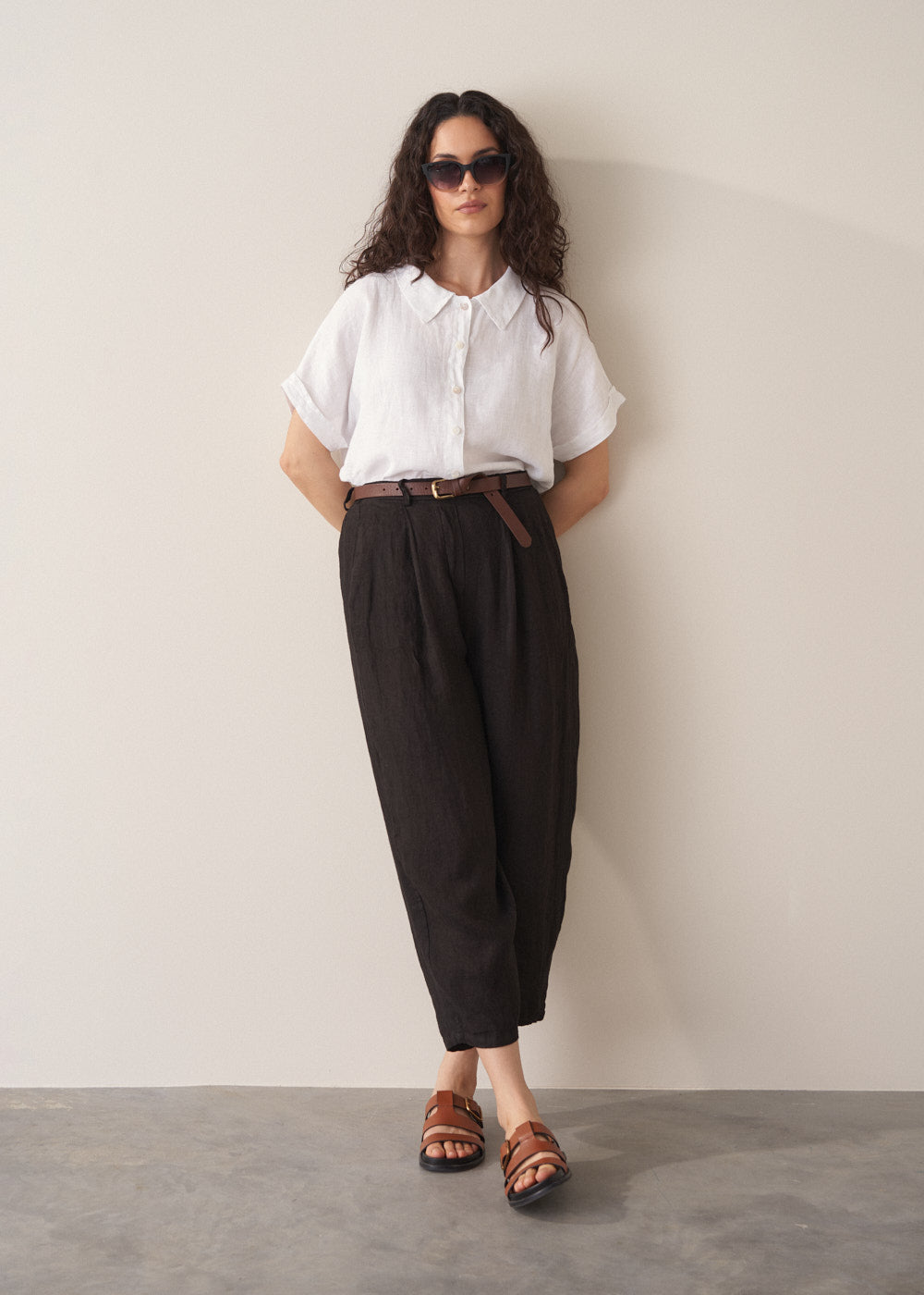 Woman wearing white linen shirt and black linen barrel leg trousers