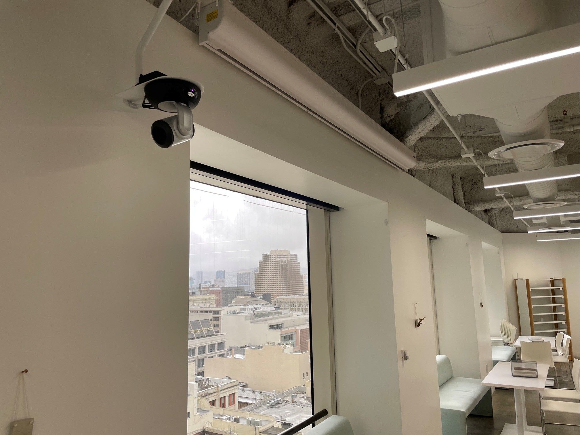 Camera mounted on wall near window in modern office space.