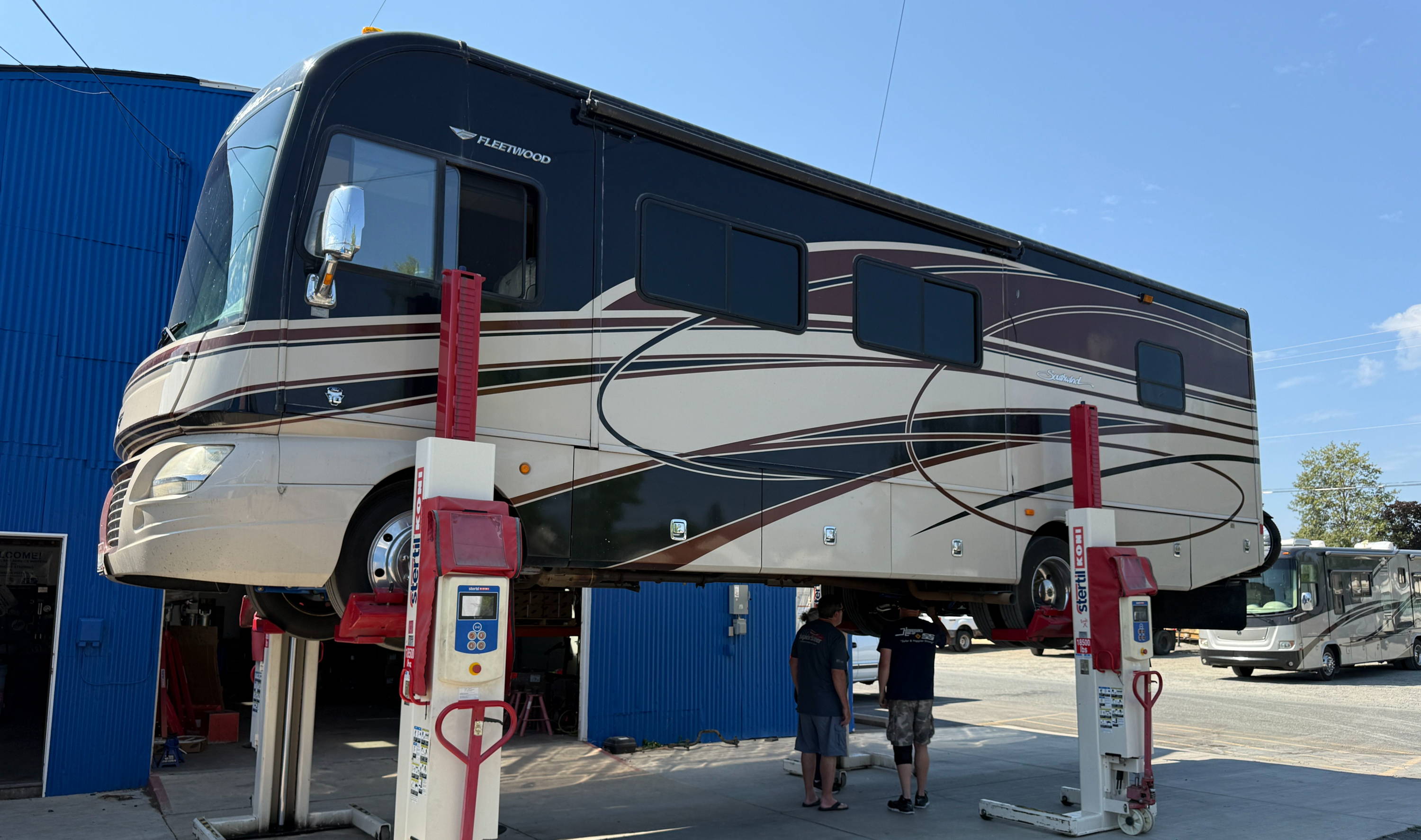 A recreational vehicle elevated on a lift in a service area.