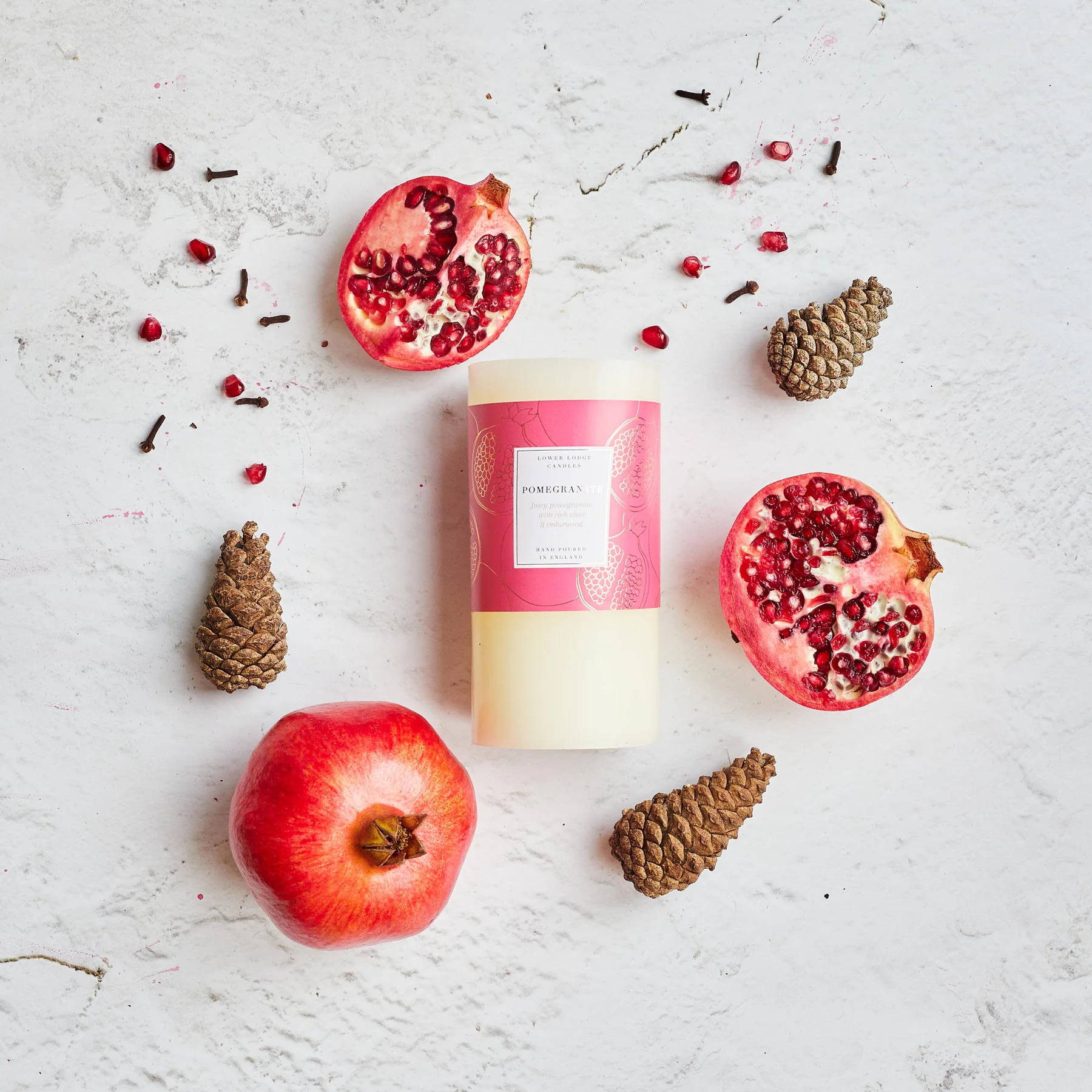 Sandalwood & Cashmere Luxury scented candle from Lower Lodge Candles Colour Pop! collection pictured with its cardboard tube packaging against a bright pink background with wood chippings