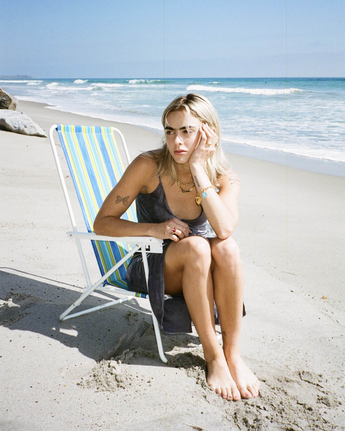 Model on the beach wearing SVNR slip midi dress, Mondo Mondo jewelry and Laura Lombardi Jewelry.