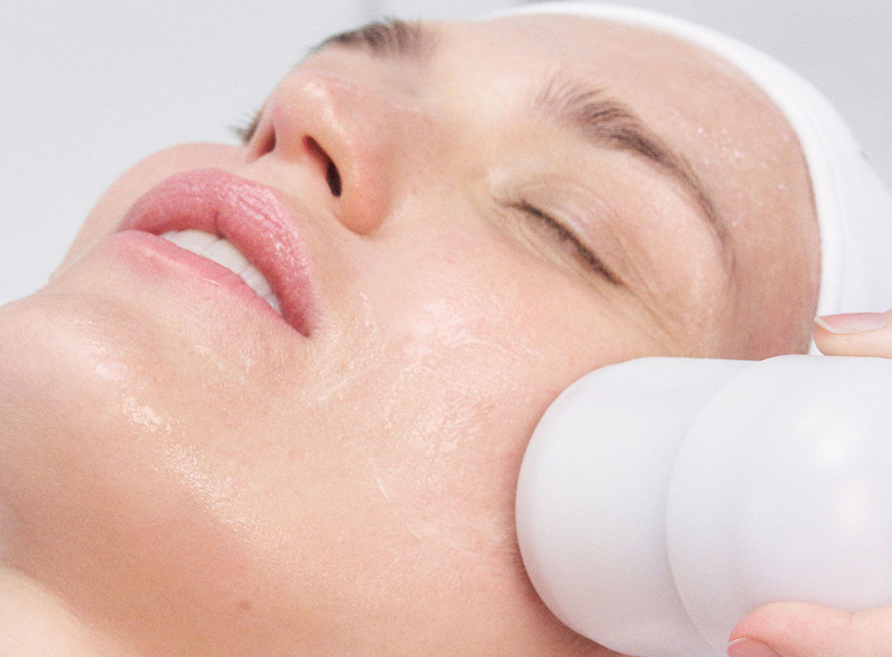 Woman receiving a facial treatment with a device on her cheek.