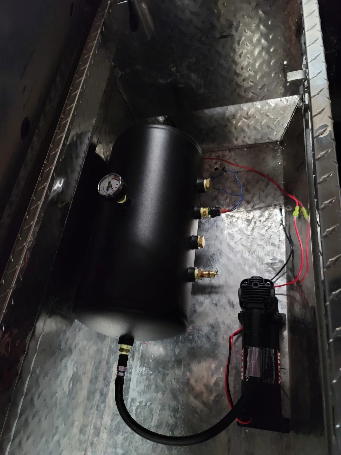 Air tank and compressor setup mounted inside a metal toolbox in the truck bed
