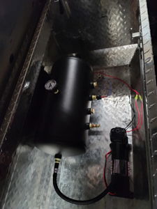 Air tank and compressor setup mounted inside a metal toolbox in the truck bed
