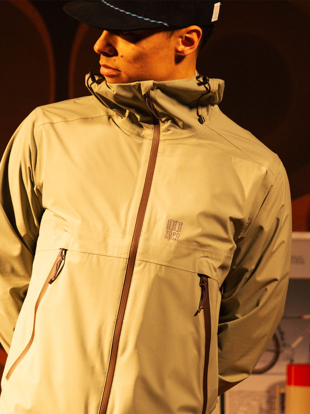 Person wearing a light-colored jacket and cap, posing indoors.