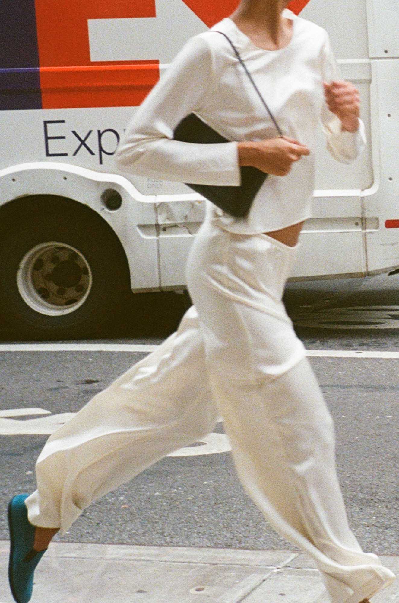 Woman running down street with bag in hand