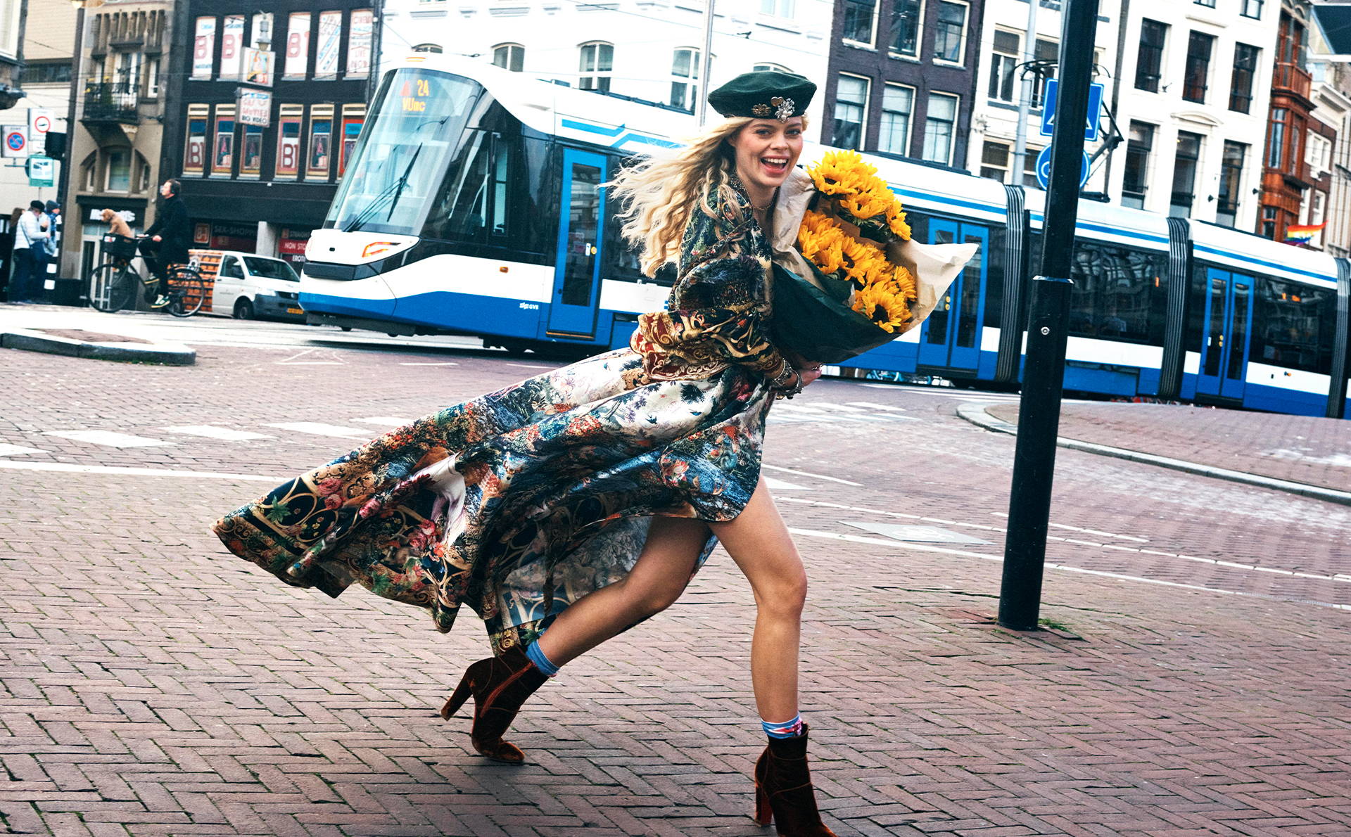 MODEL WEARING TAPESTRY TOTEMS PRINT LONG COAT WALKING THROUGH THE NETHERLANDS WITH SUNFLOWERS