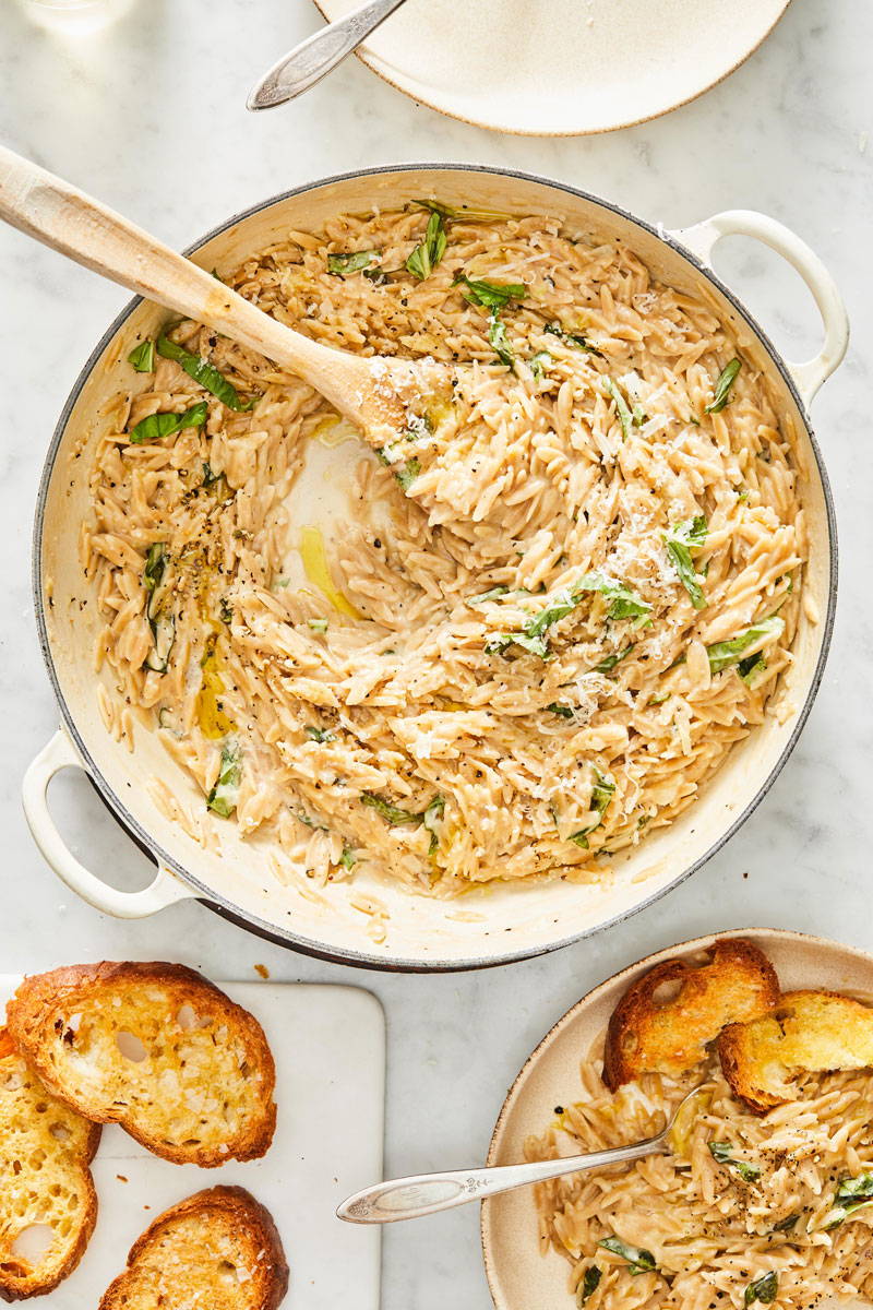 creamy whole wheat orzo in pot with serving spoon