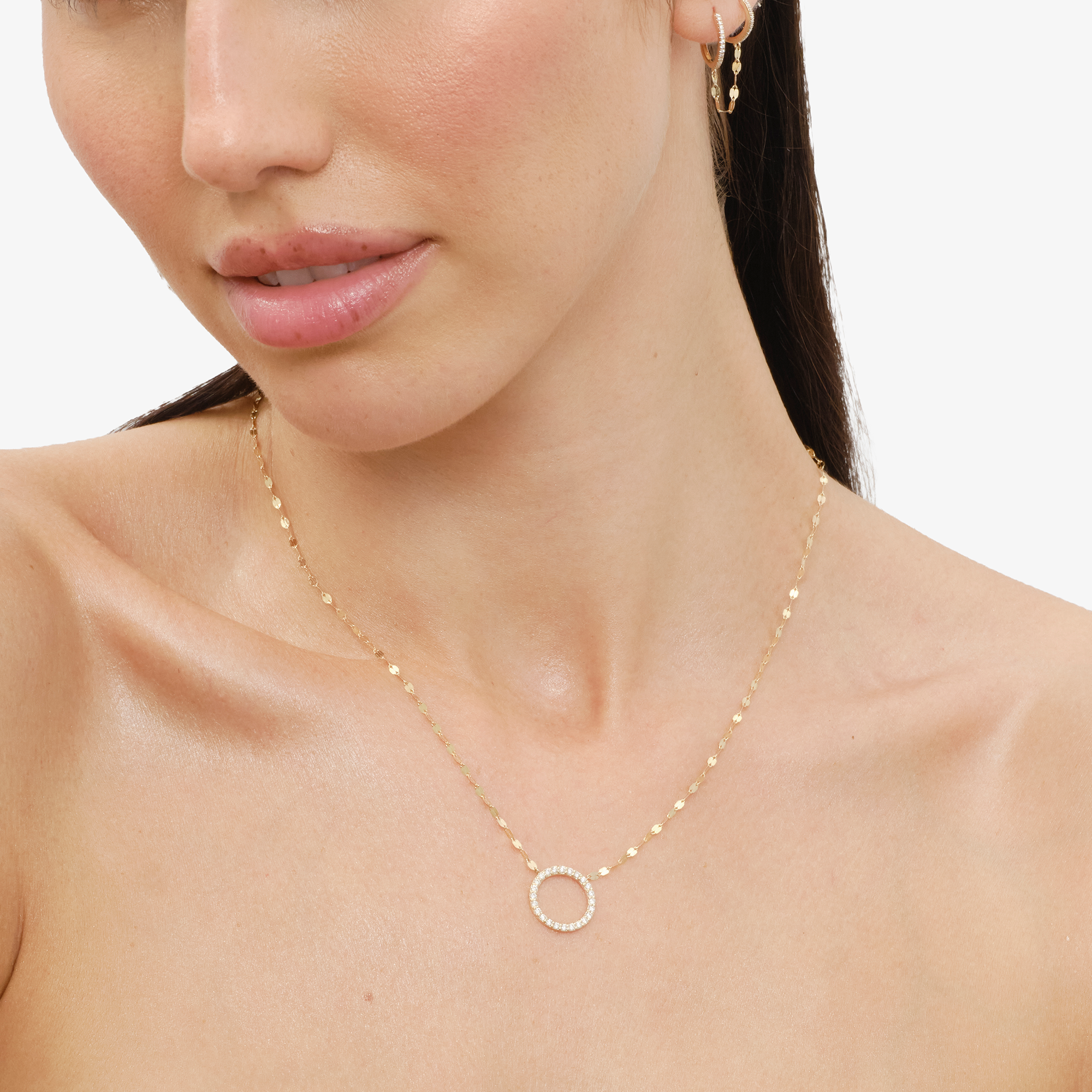 Woman wearing a delicate gold necklace with a circular pendant.