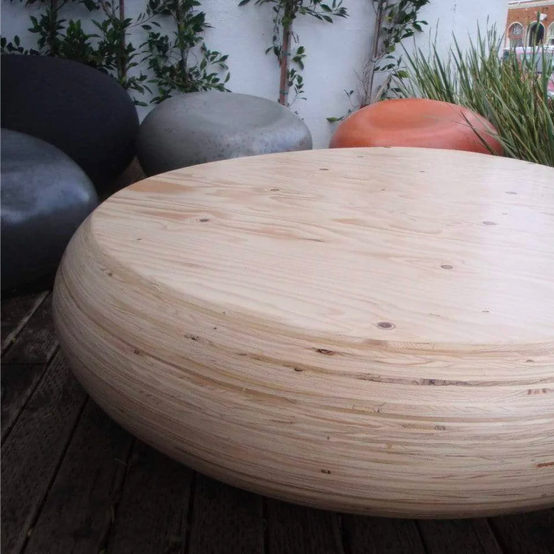 A layered wooden pebble outdoor coffee table with pebble seats surroudning it.