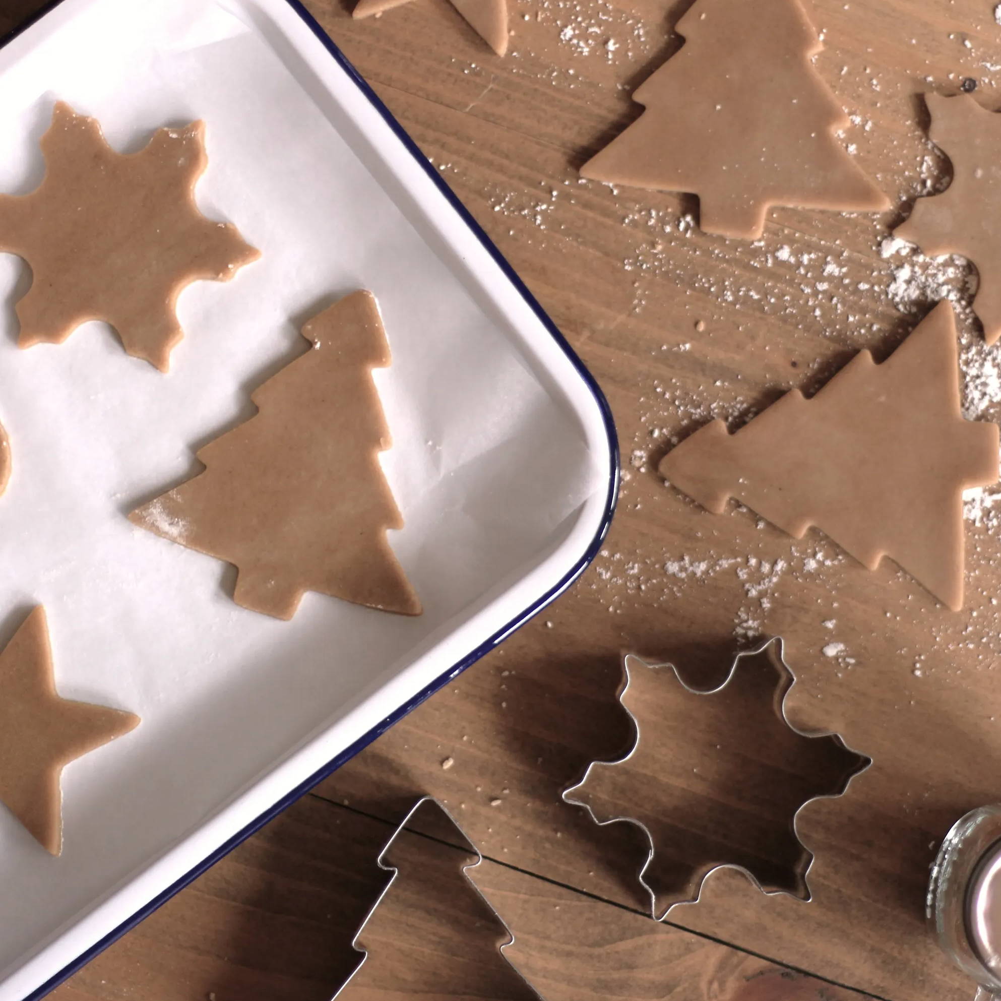 Festive Christmas tree biscuits lining a  baking tray