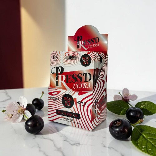 A box of Pressed Ultra with cherries and leaves on a marble surface.