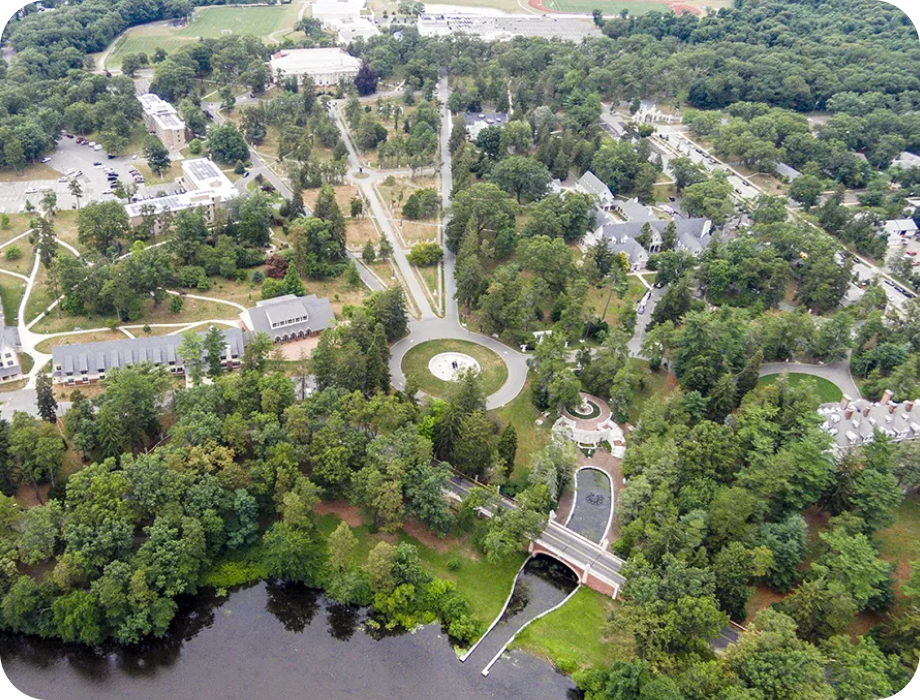 Aerial view of a wooded area with buildings and a pond.