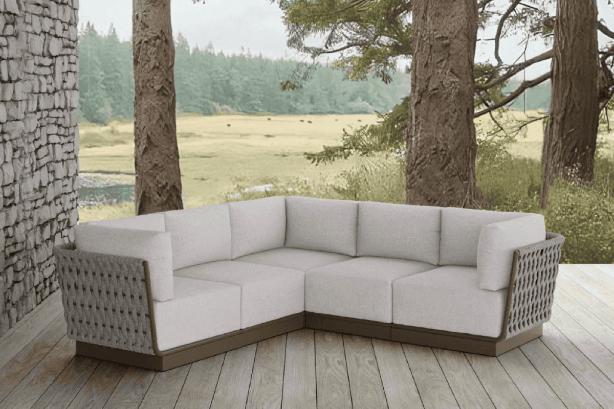 Modular outdoor sectional sofa with weather-resistant cushions and woven side panels on a covered woodland deck