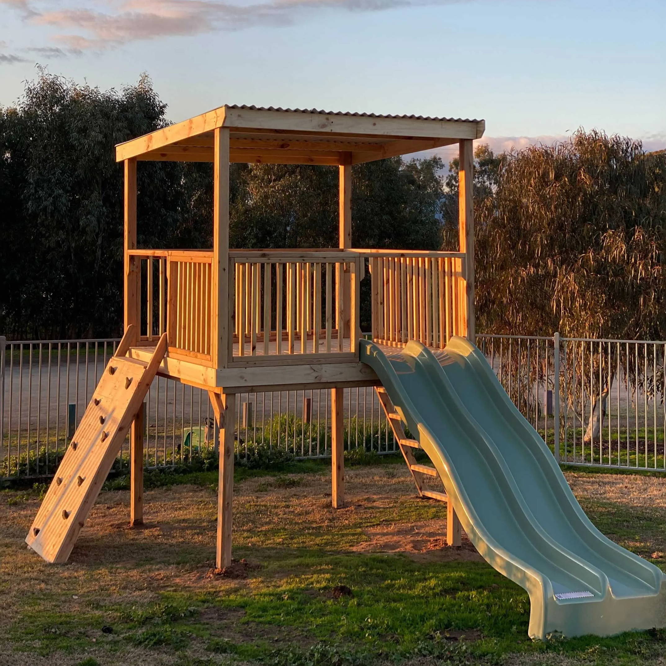 A raised platform cubby houses with a ladder and slides