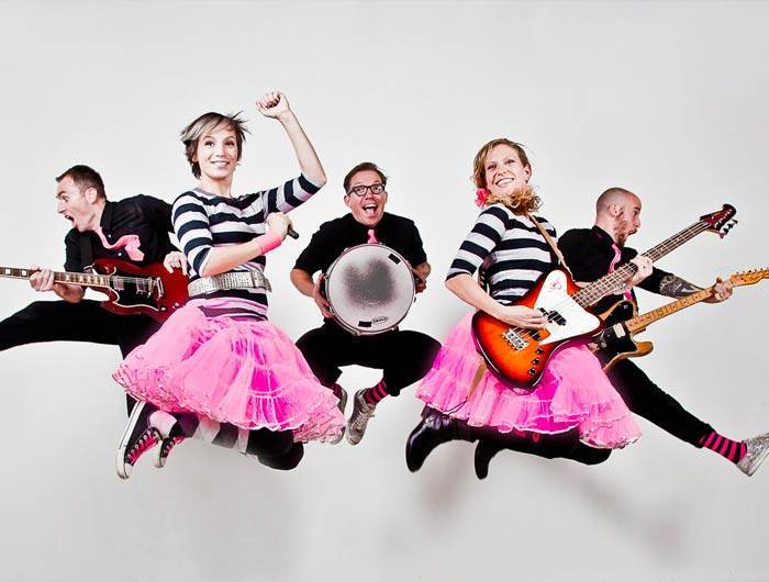 Band in black and hot pink jumping with instruments