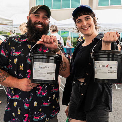 Two attendees holding free Chromaline screen printing emulsion at the Ryonet open house
