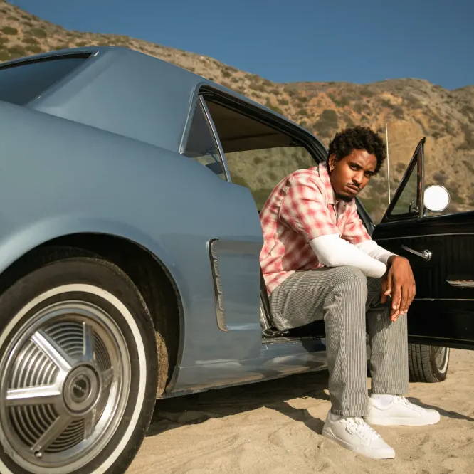 male model sitting in car wearing levi's shoes