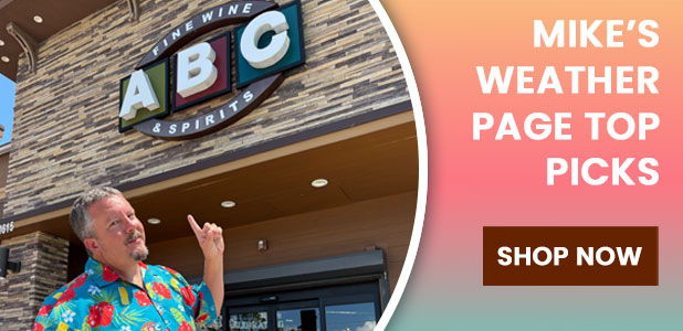 Man in colorful shirt pointing at a store sign.