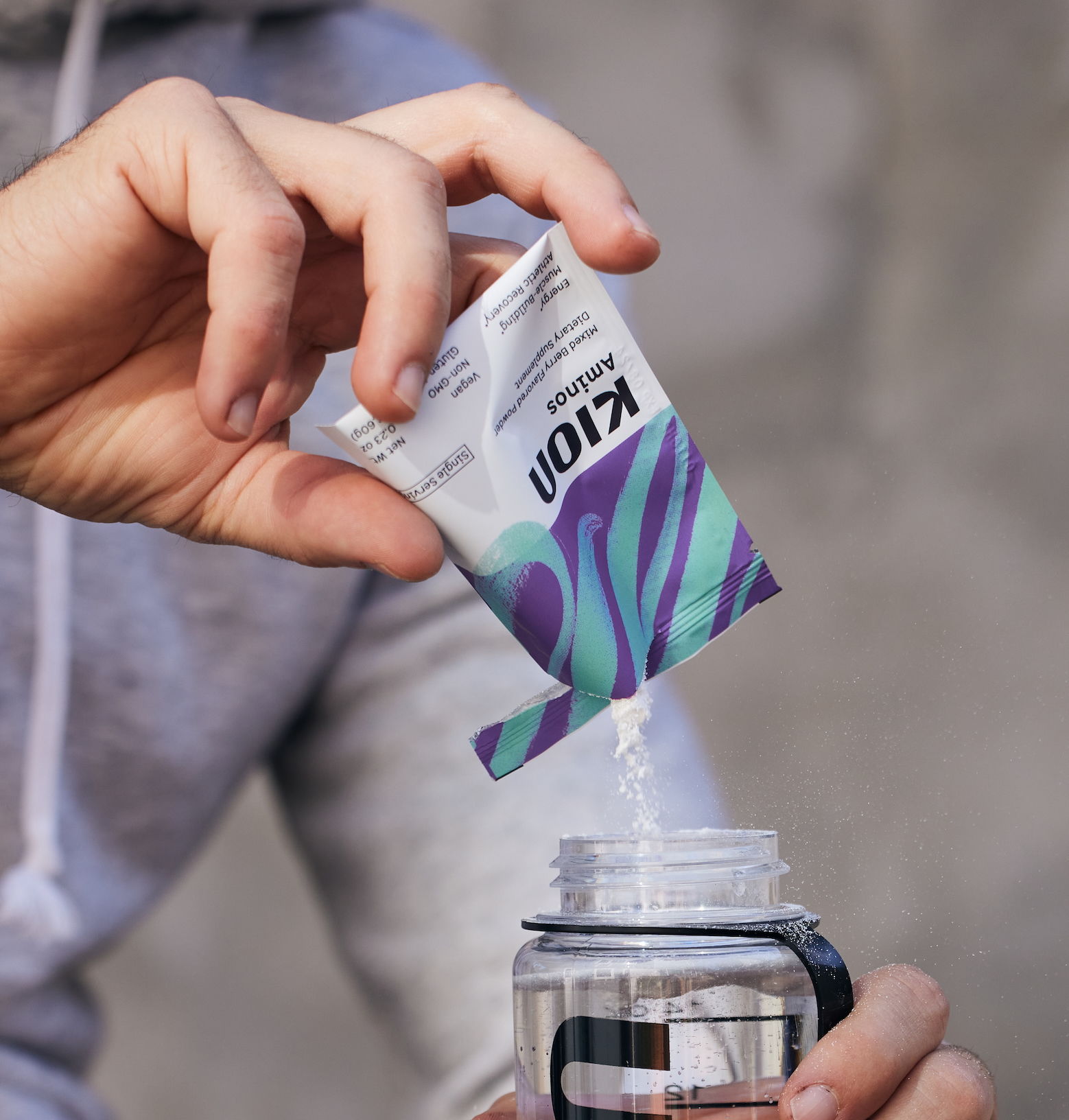 Person pouring a packet into a water bottle.
