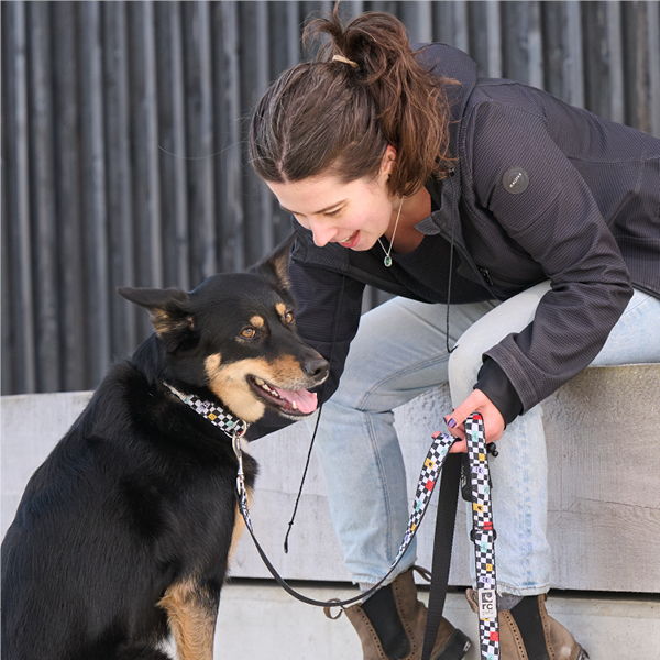 Woman interacting with a black and tan dog on a leash.