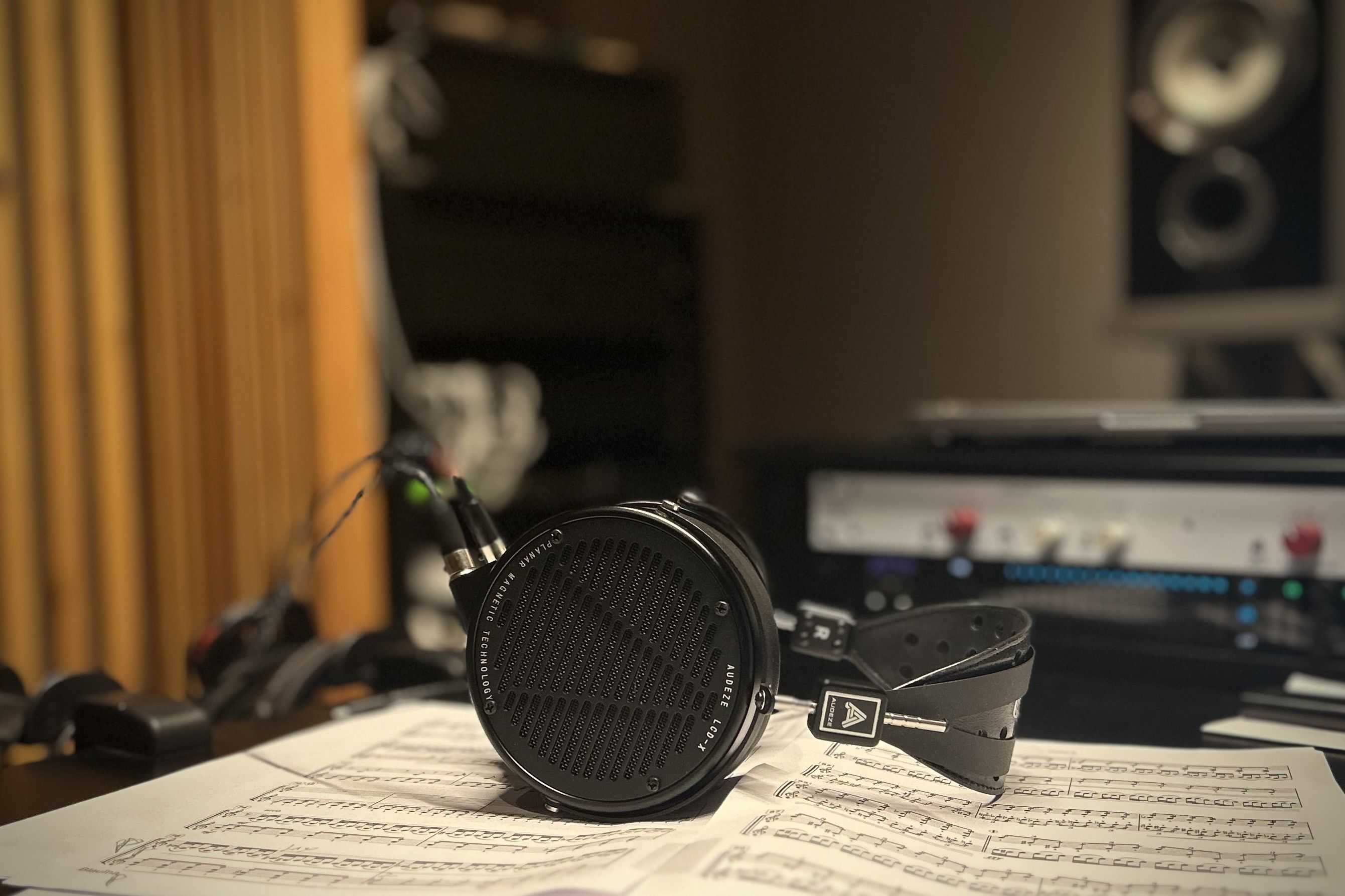 Audeze LCD-X headphones resting on sheet music in a studio setting.