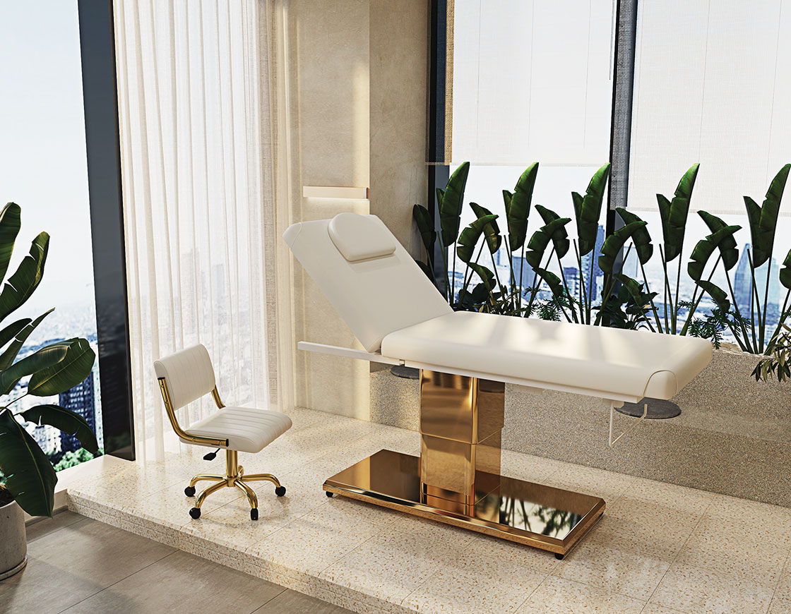 A modern treatment room with a bed and a chair beside plants.