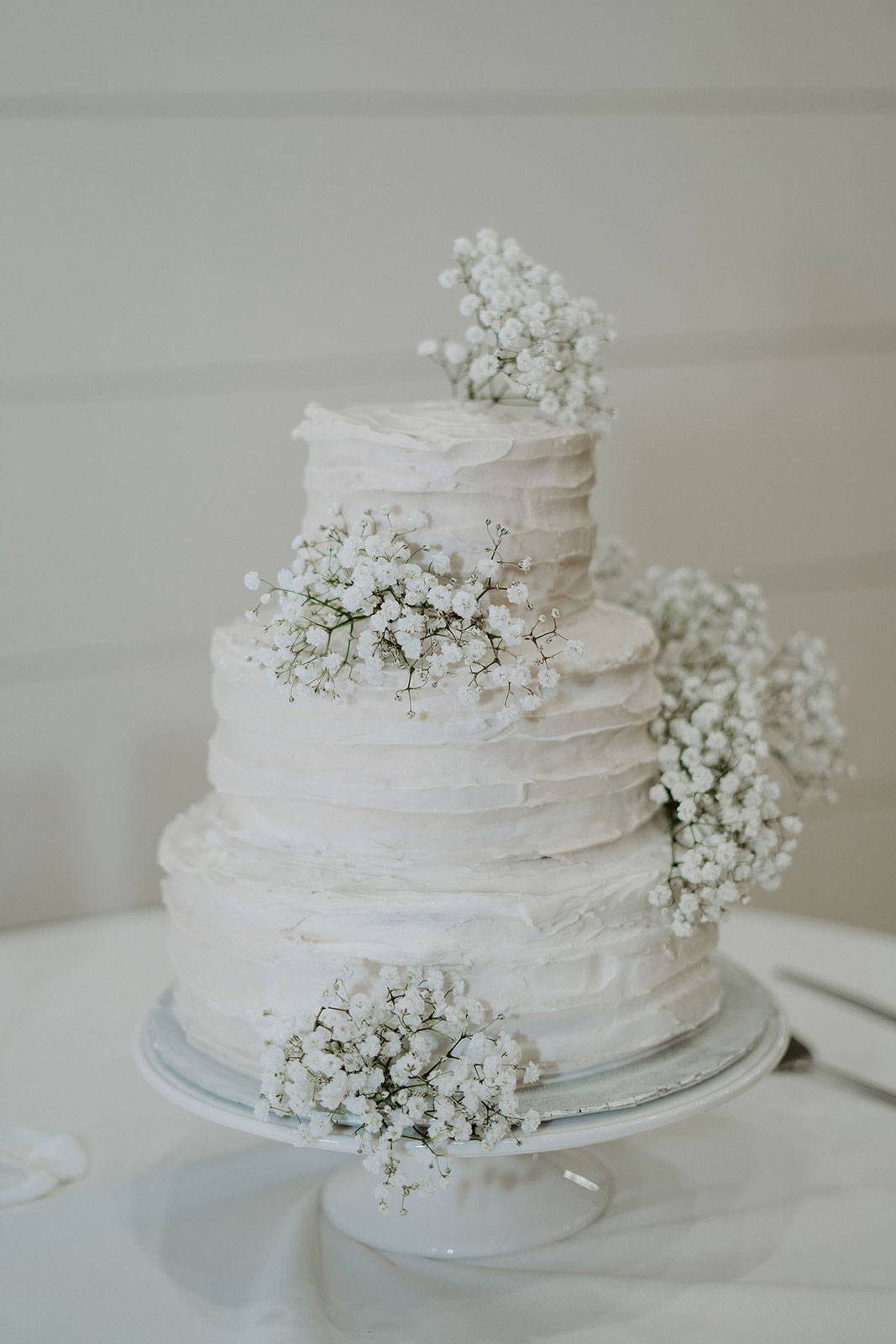 White tiered wedding cake with babies breath flowers