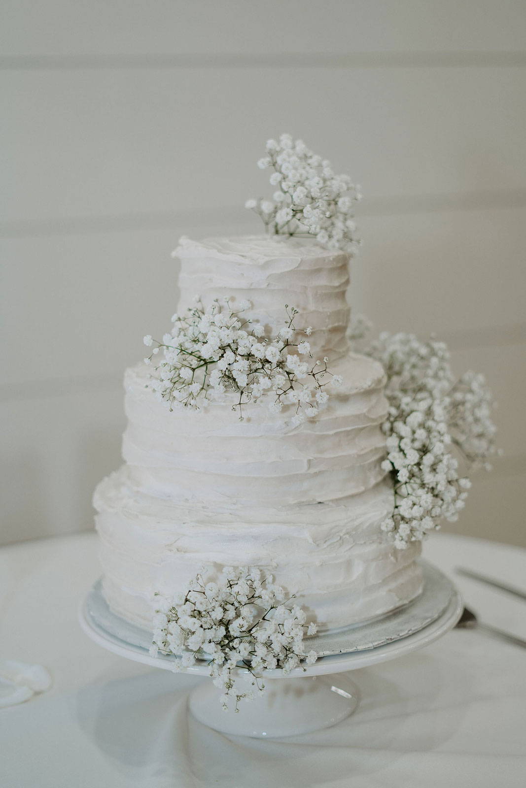 Weiße stufige Hochzeitstorte mit Baby-Atem-Blumen