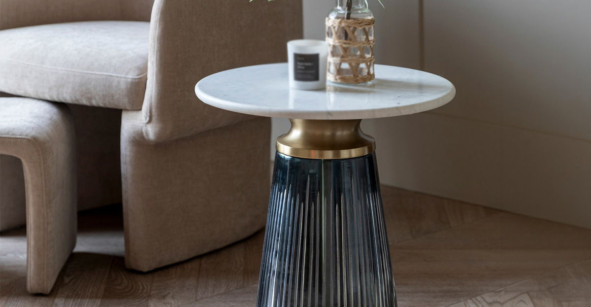 A stylish lamp table with a marble top and decorative items.