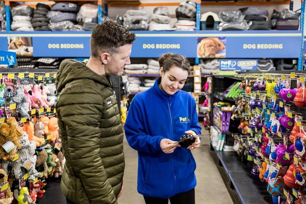 a person getting advice on selecting an appropriate toy for their dog in a pet shop
