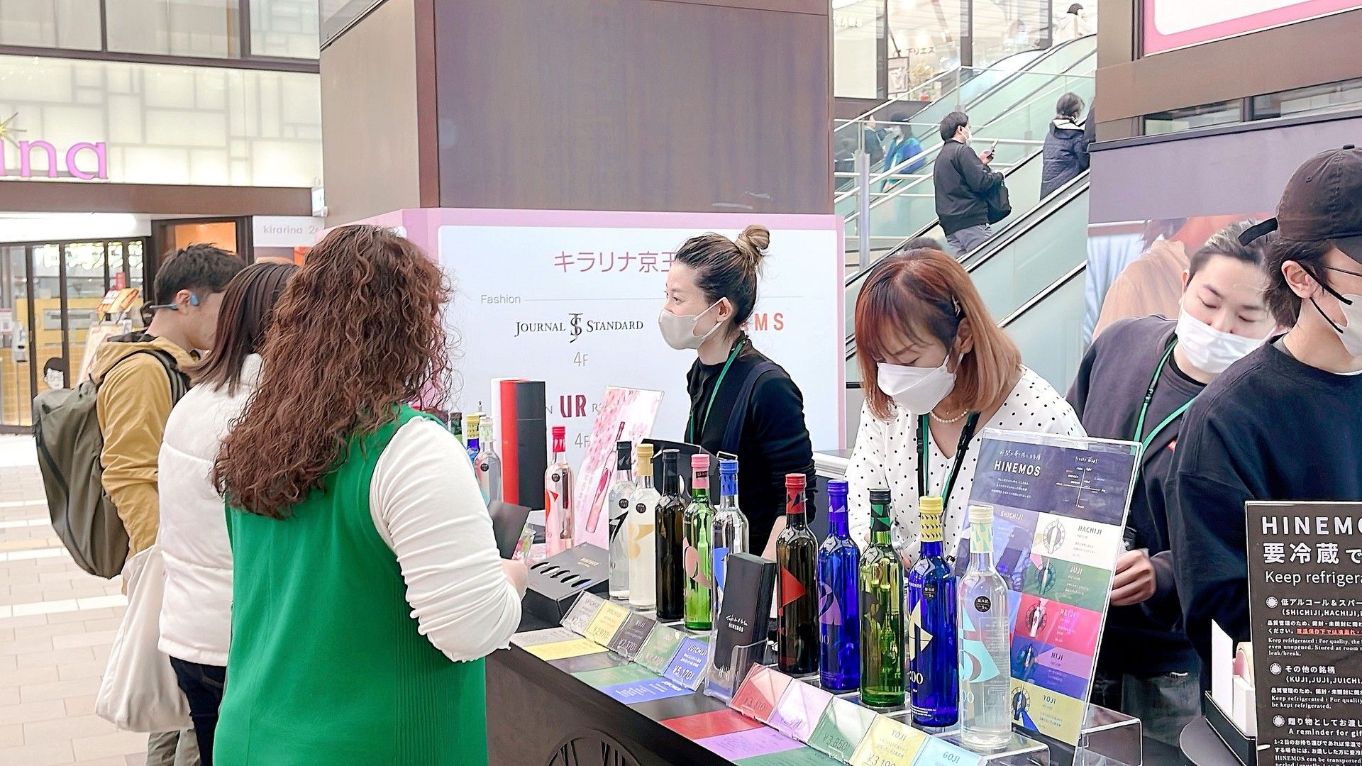 People at a promotional event examining various bottles on display.