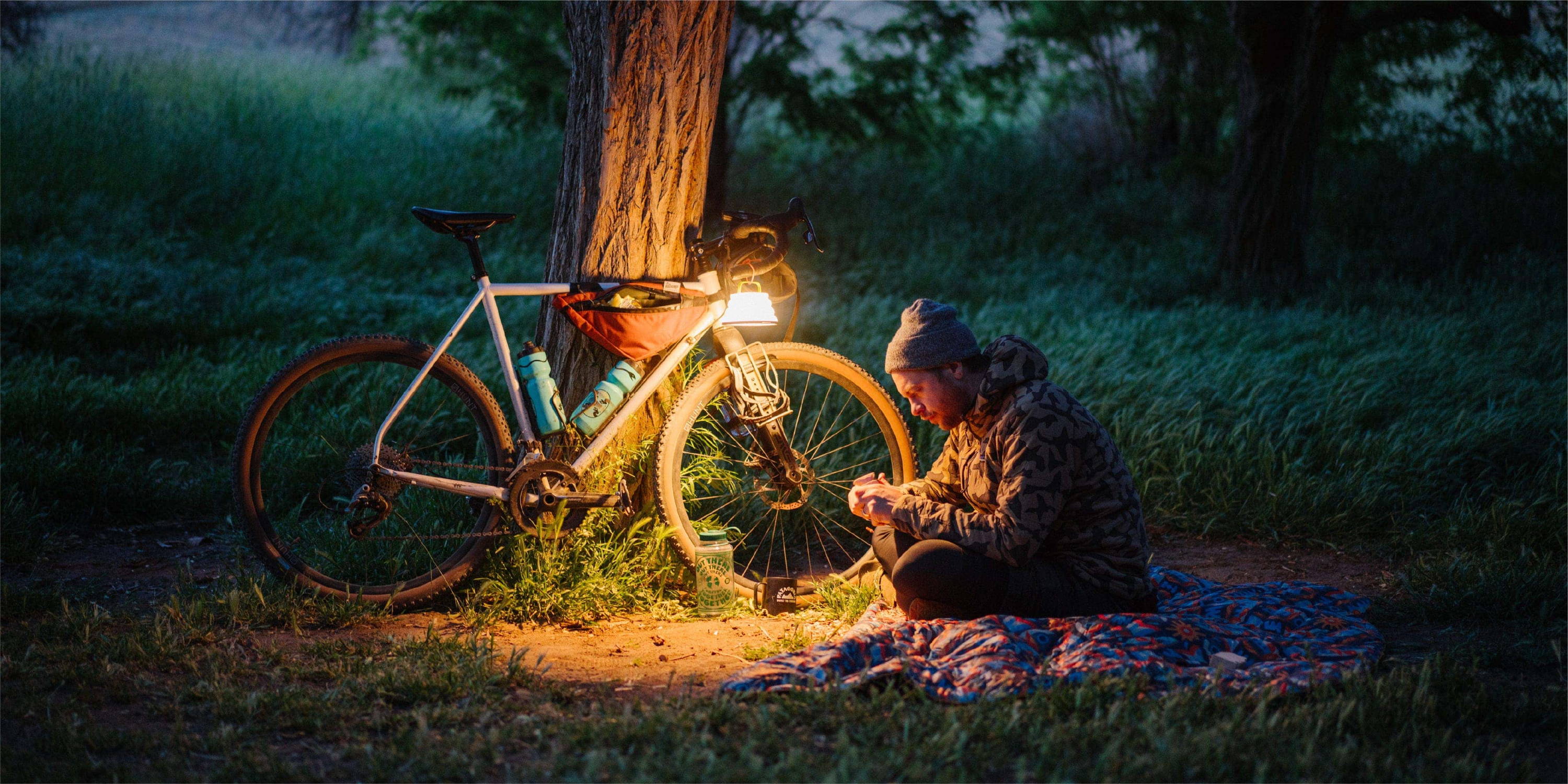 Brett Stenson carving wooden figure on Fish Are Fly blanket under light outside