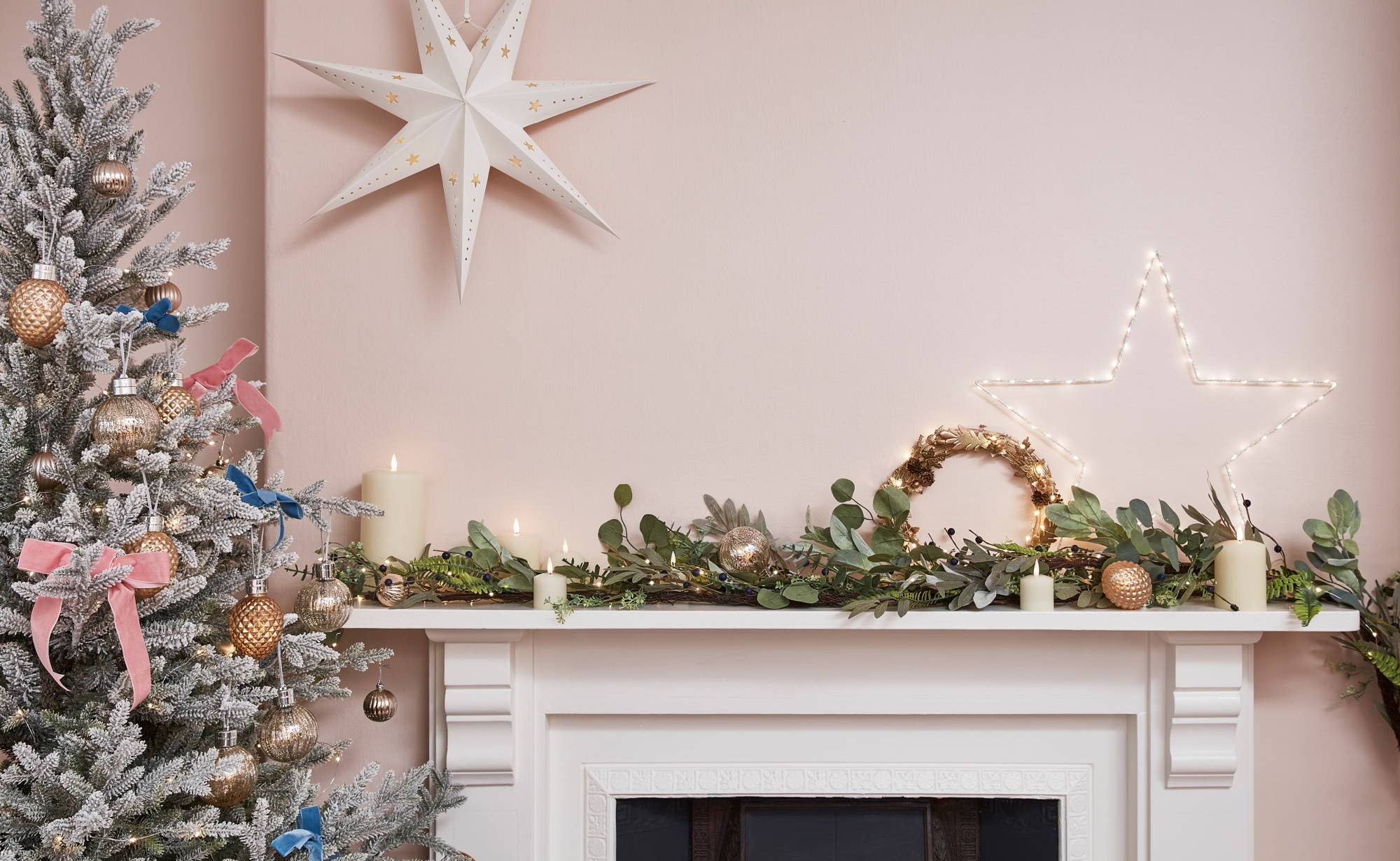 Pastel Christmas setting with a garland, star lights and snowy Christmas tree.