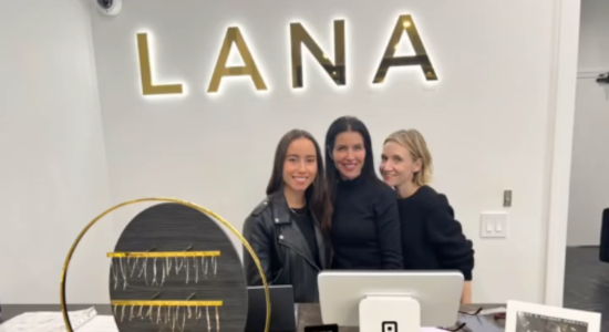 Three women smiling at a reception desk with 