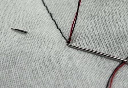 Closeup of self-threading needle piercing the quilt top