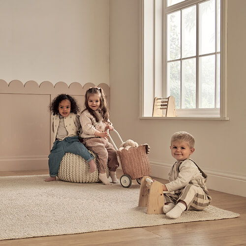 Three children playing in a cozy, softly lit room with toys.