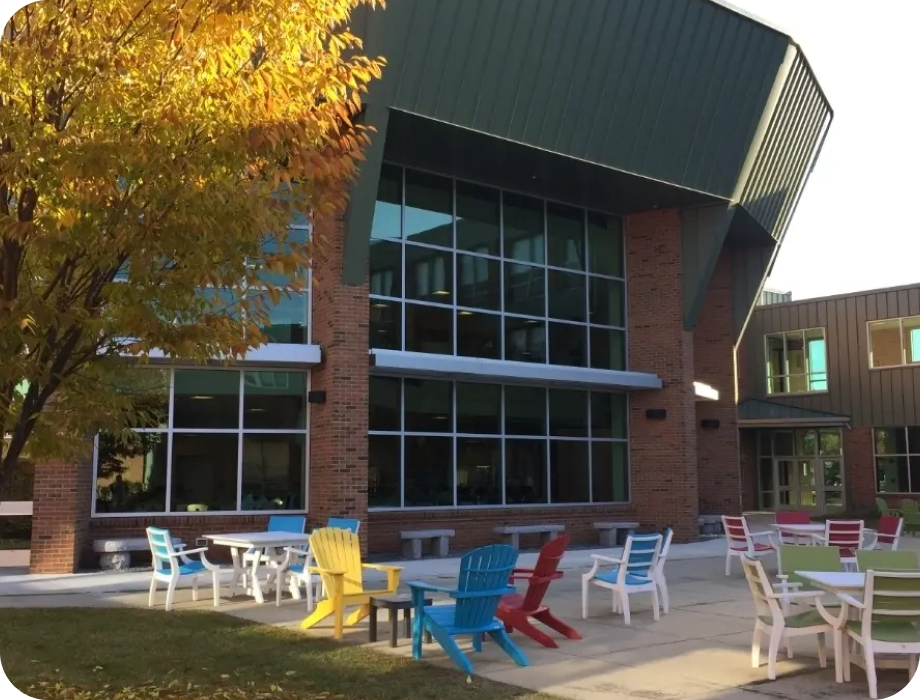 Modern building with large windows and colorful outdoor seating.