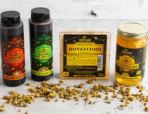 Bottles of honey products and pollen on a wooden surface.