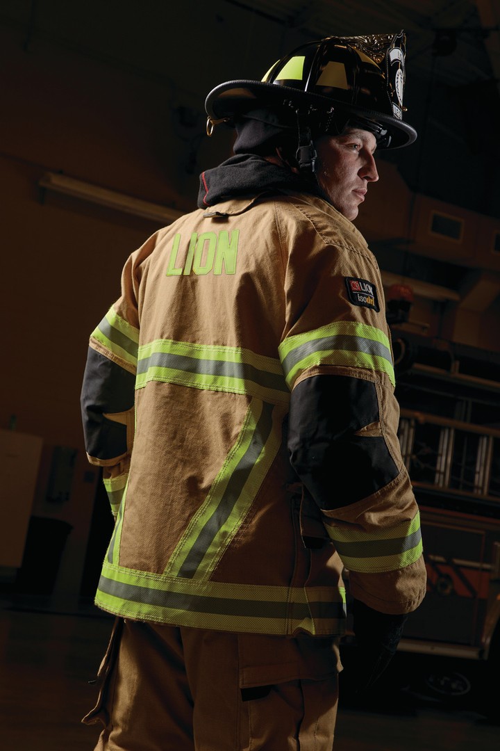 Firefighter in protective gear looking back, with reflective stripes and helmet.
