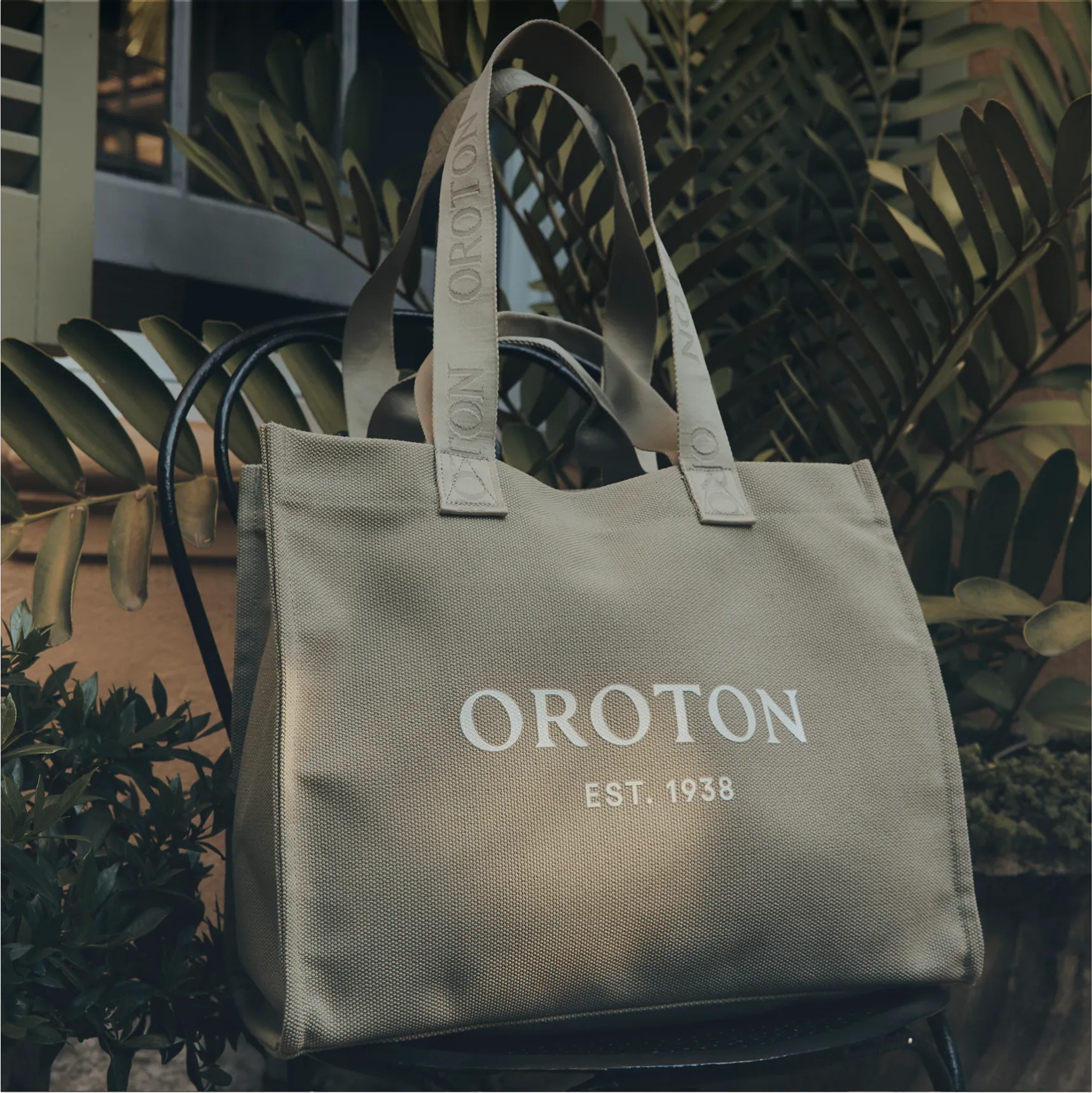 A stylish Oroton tote bag against a backdrop of greenery.