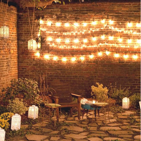 Outdoor setting with festoon lights, lanterns and plants.