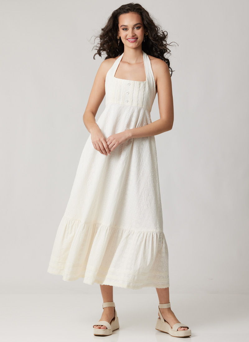 Model wearing a white halter neck maxi dress with a tiered hem.
