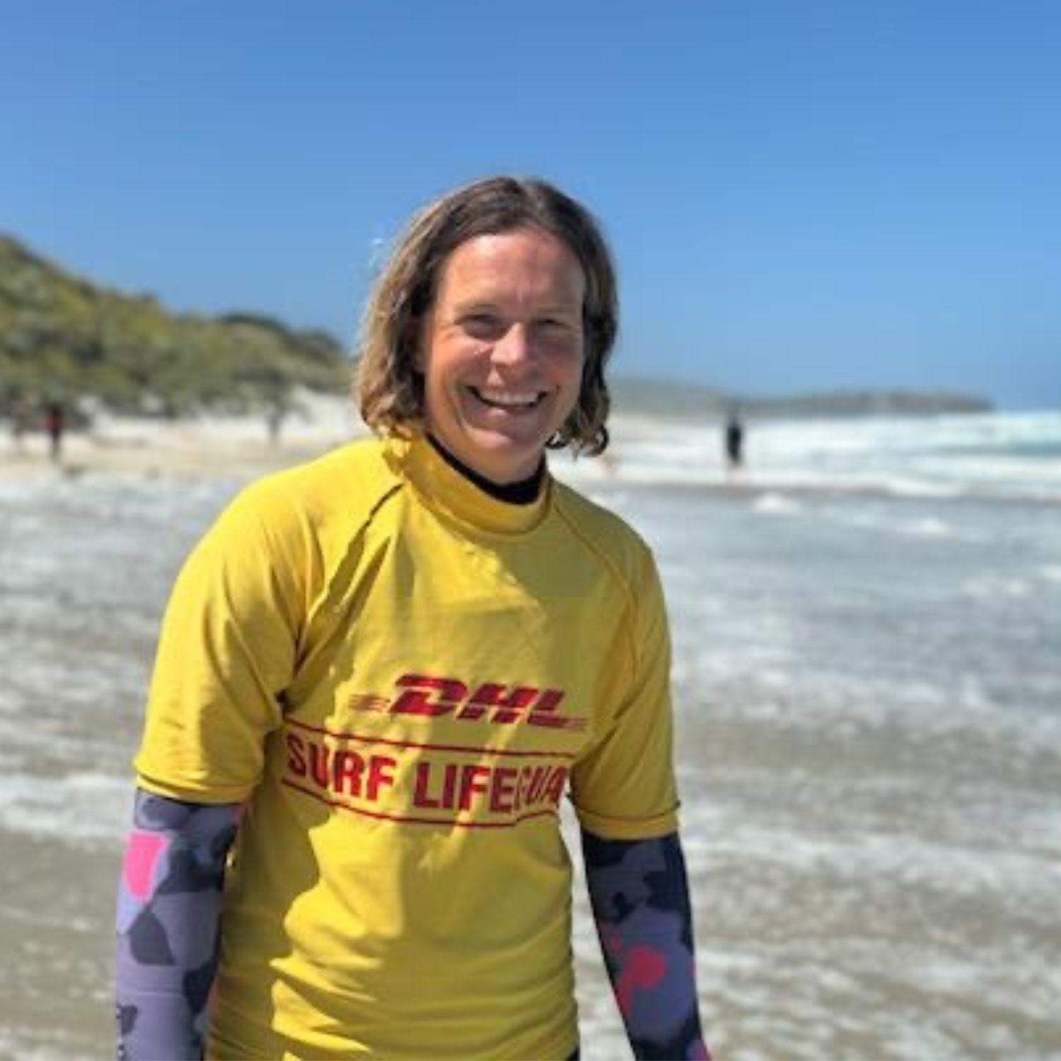 Person in a yellow surf life saving shirt at the beach.