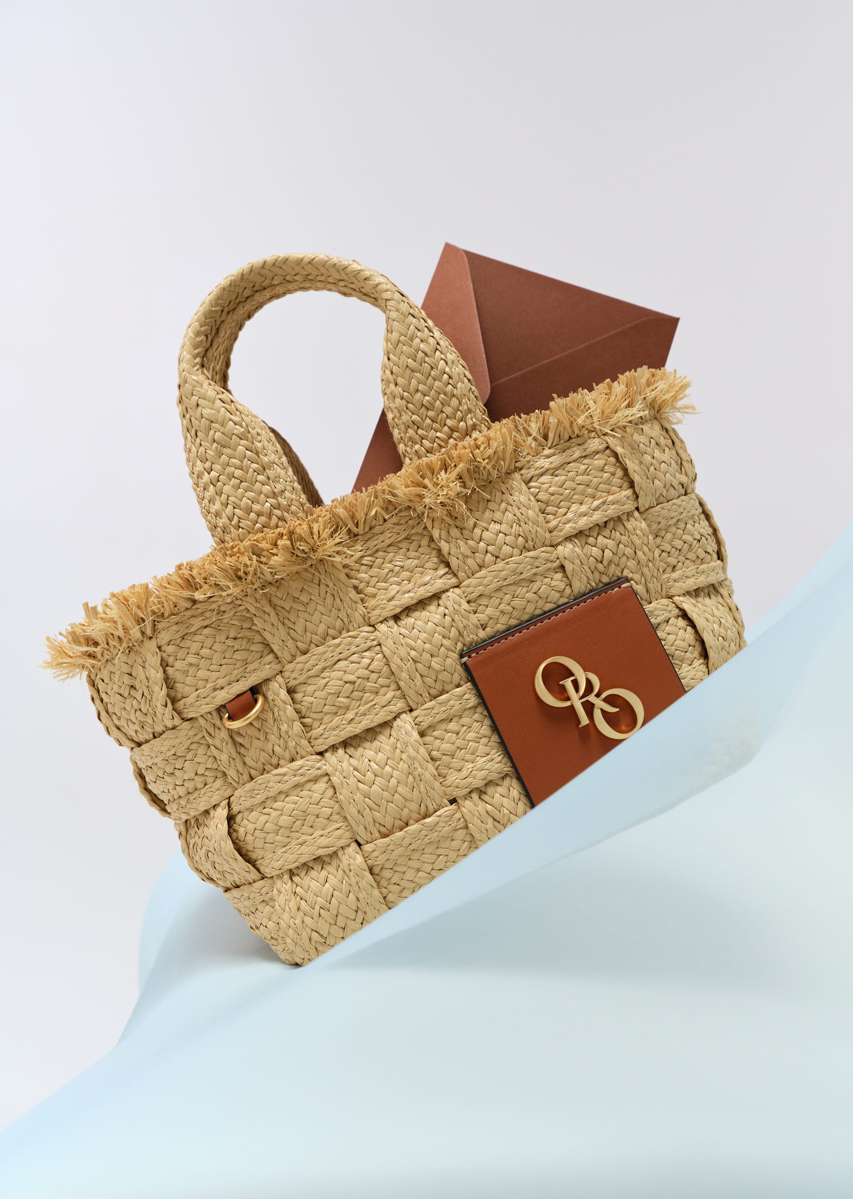 Woven straw handbag with brown accents and a decorative logo.