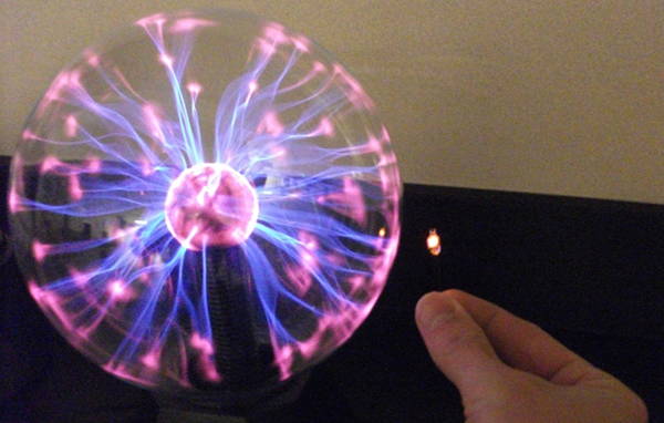 The LED bulb glows brighter as it approaches the plasma globe
