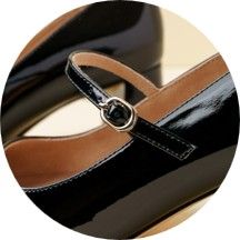 Black patent leather heels with a strap and buckle detail.