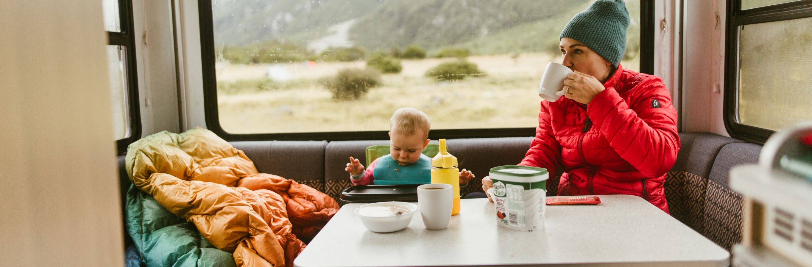 a mother and baby sitting at a table in a camper vehicle